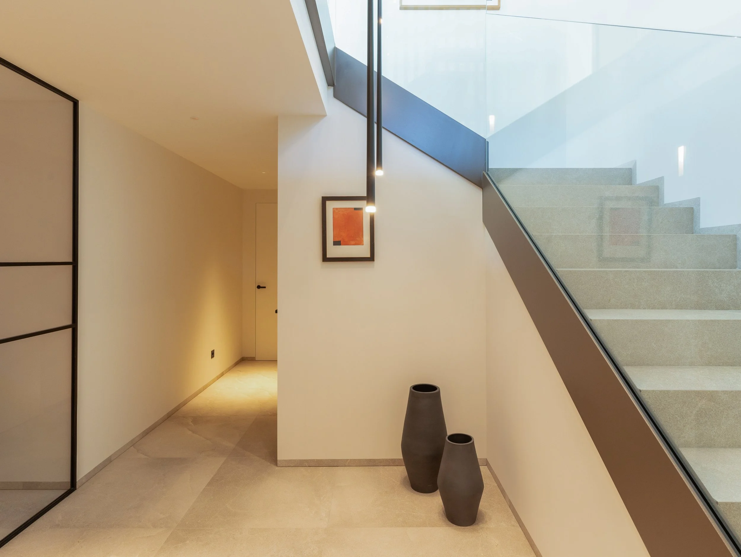 Interior moderno de casa u oficina con escaleras, pintura blanca, cuadros en la pared y decoración minimalista.