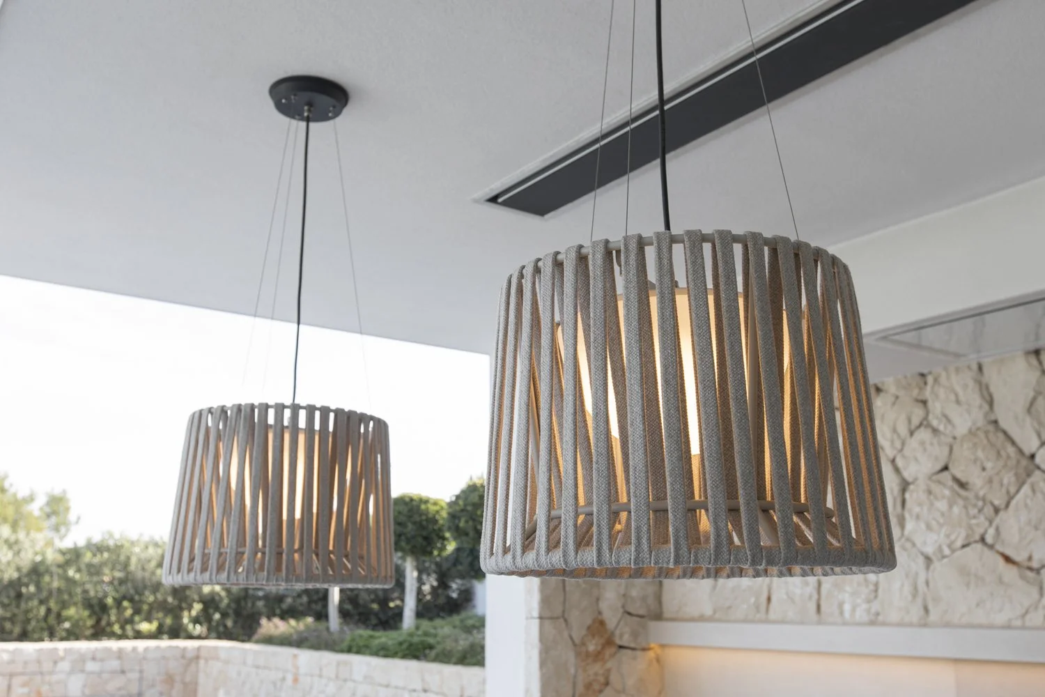 Dos lámparas de techo de diseño rústico con pantallas de listones de madera que emiten luz cálida en un espacio interior.