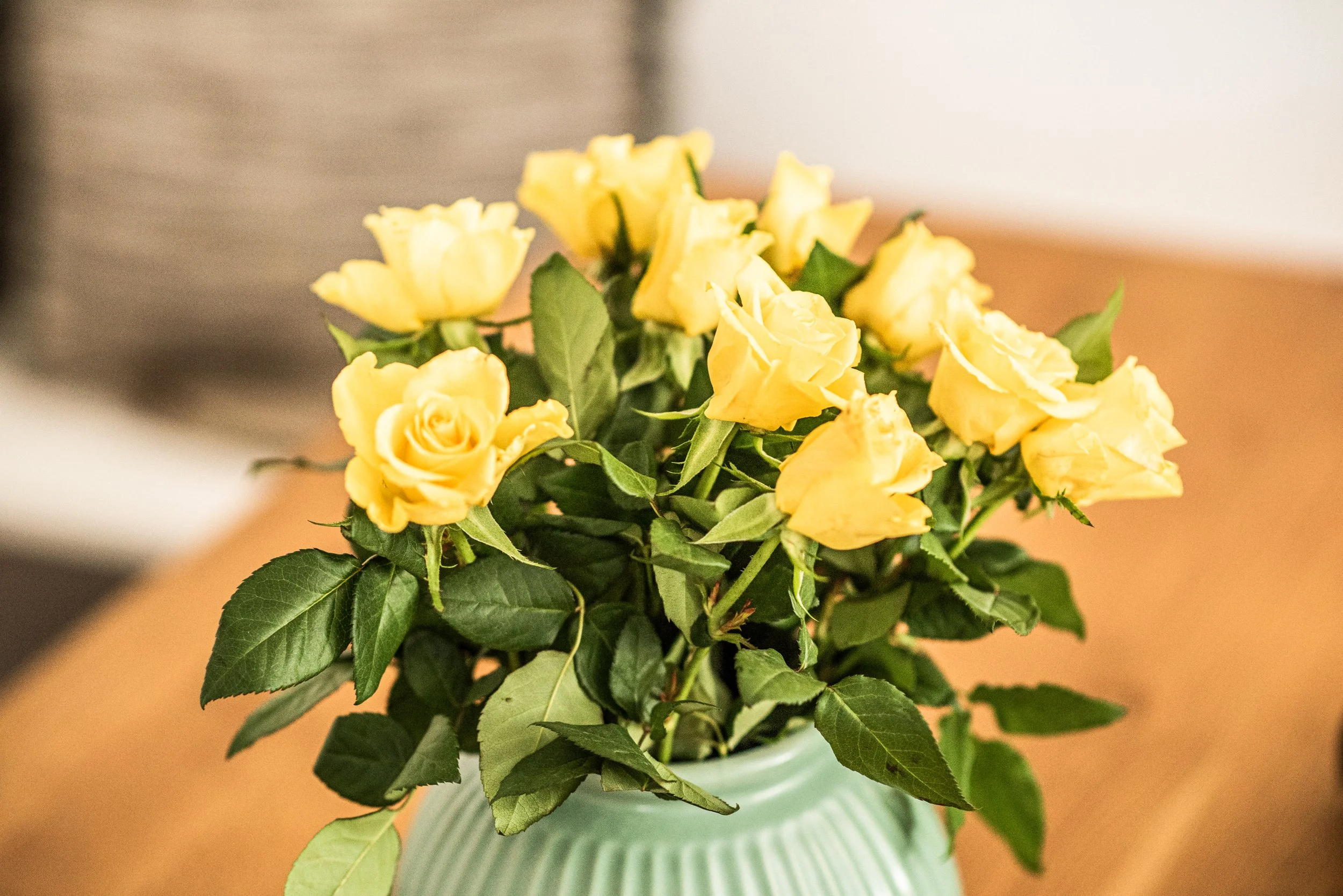 Gelbe Rosen in einer Vase auf einem Tisch.