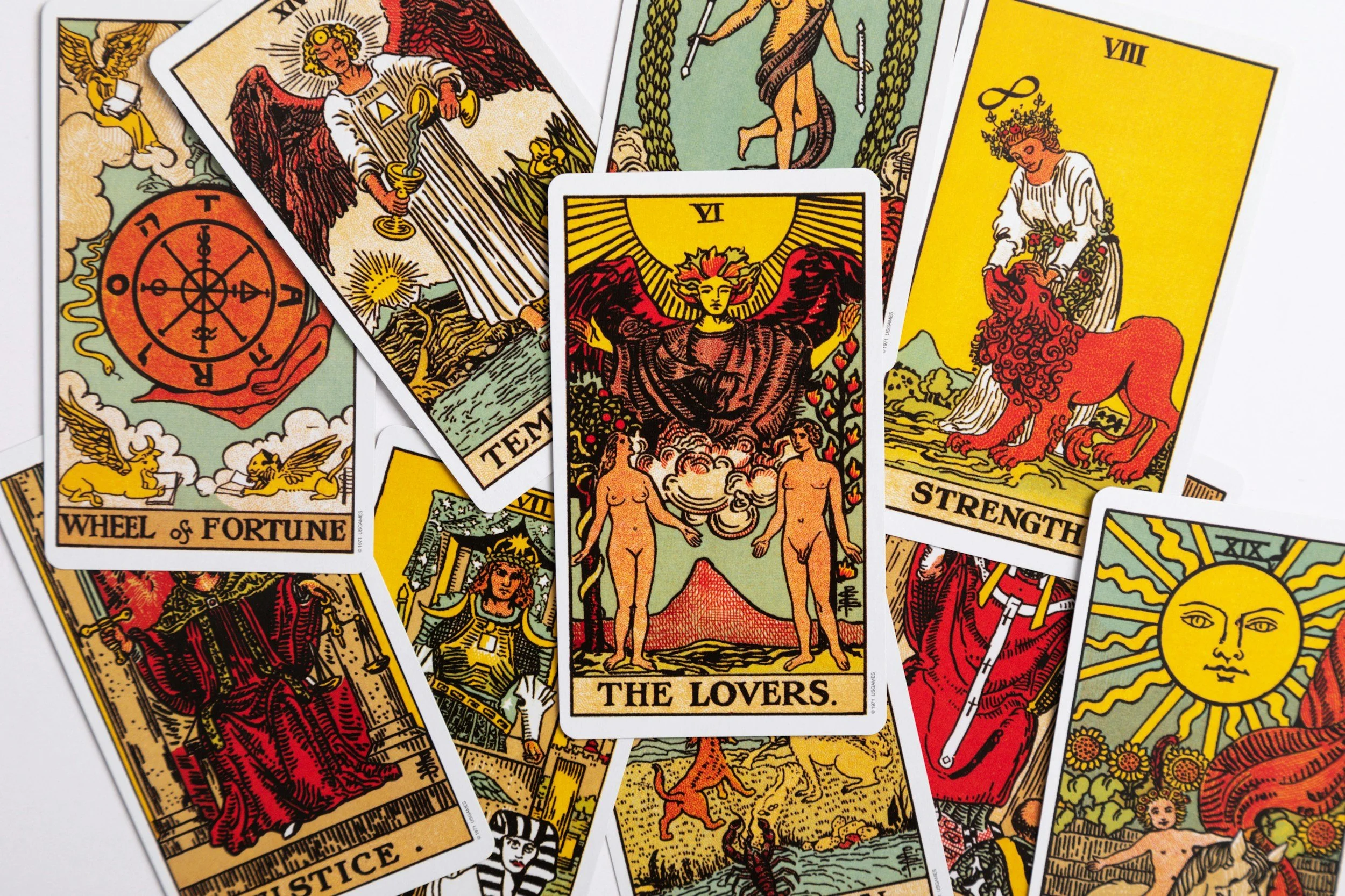 A pile of Ryder-Waite Tarot cards, showcasing the Major Arcana. Several cards are identifiable including The Lovers, Strength, Wheel of Fortune and The Sun.
