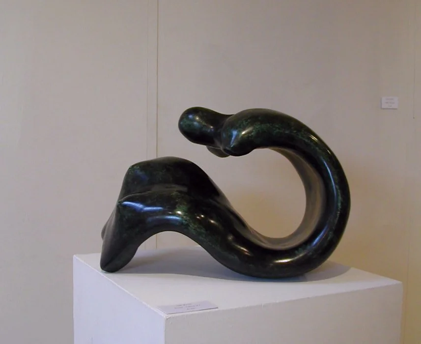 Black abstract sculpture on a white pedestal in an art gallery.