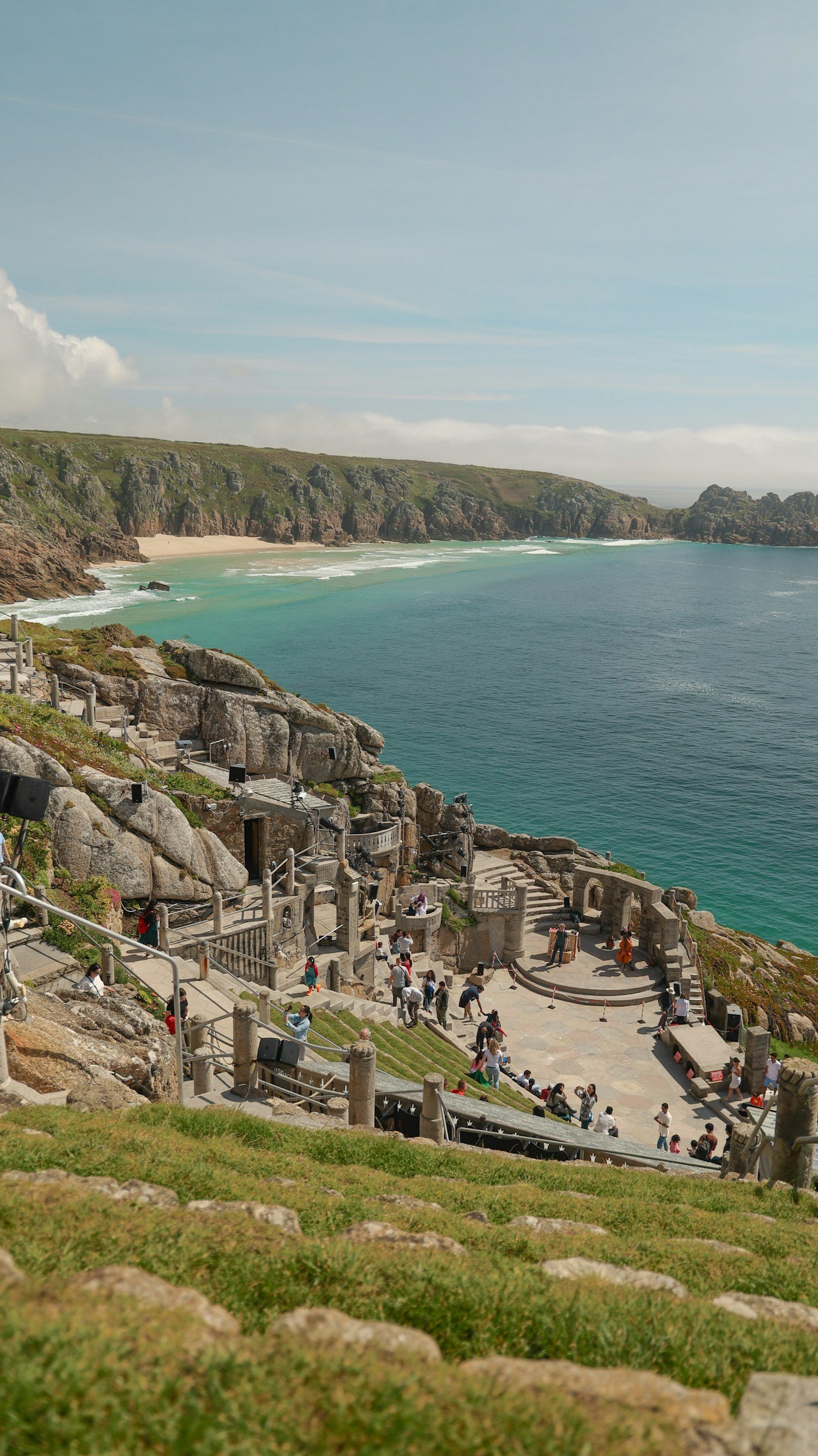 The Minack Theatre in cornwall with waves and sandy beach behind it.