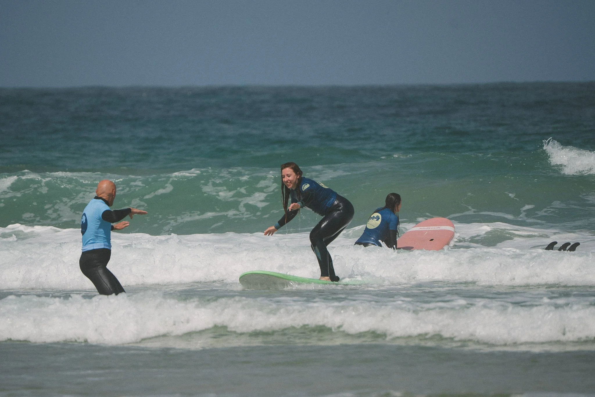 Surfer standing on a board in a small wave during a Cornwall lesson.