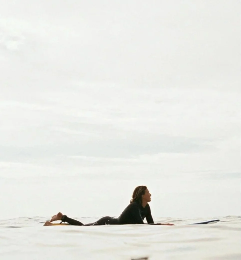 woman laying on surfboard in sea