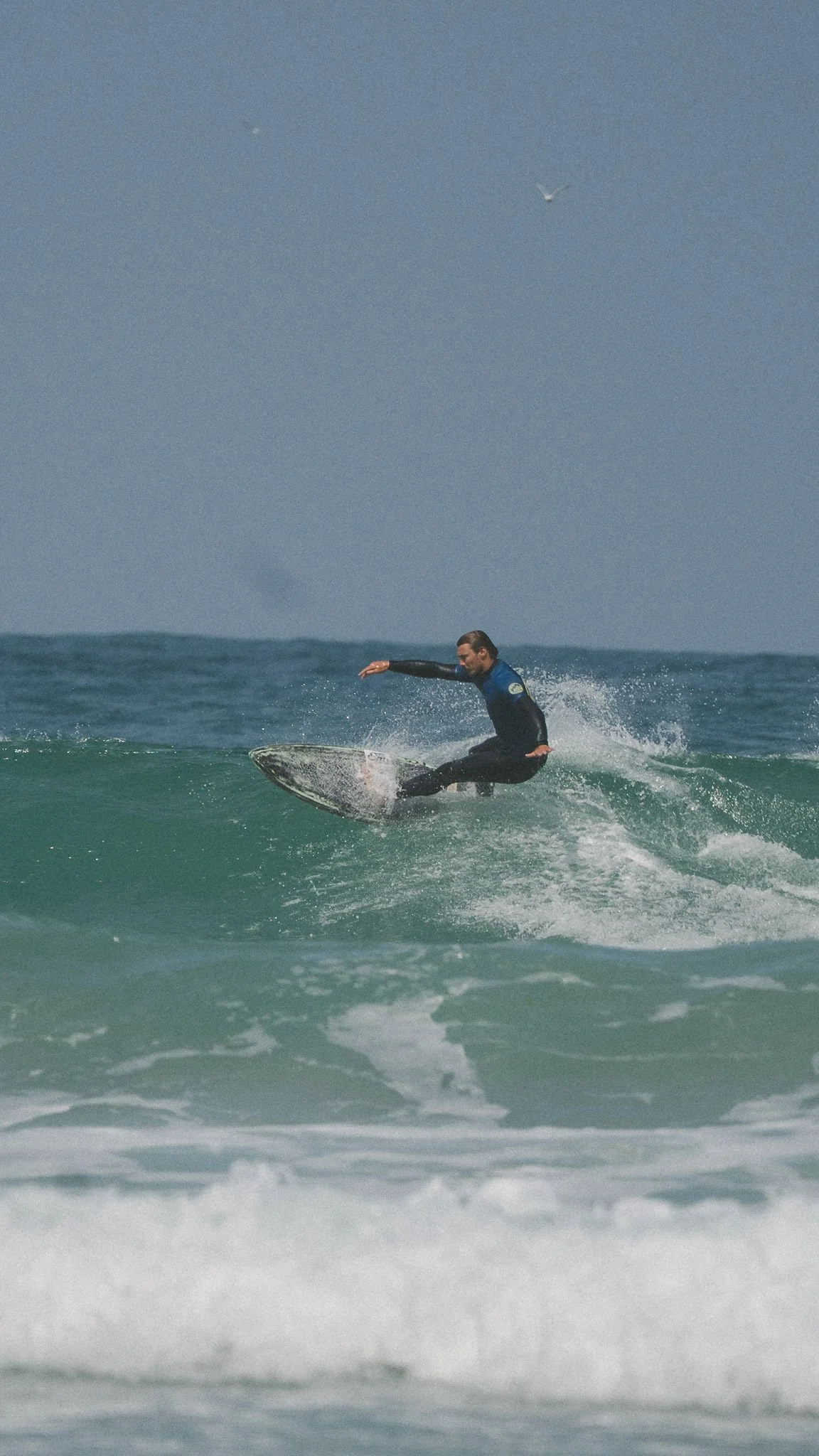 Surfer riding a green wave during intermediate surf coaching in Cornwall.
