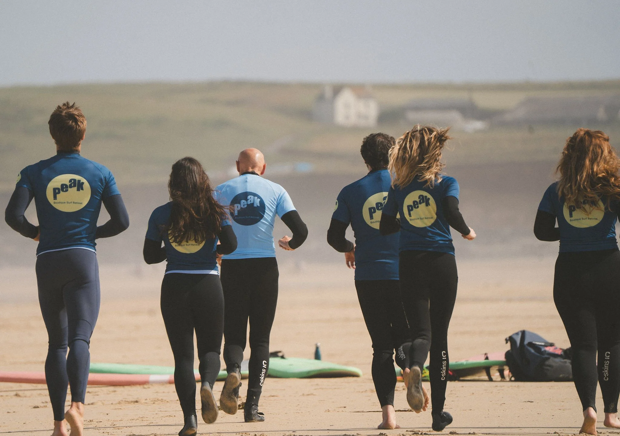 Peak surf coach leading the guests heading towards the sea for a lesson in Cornwall.