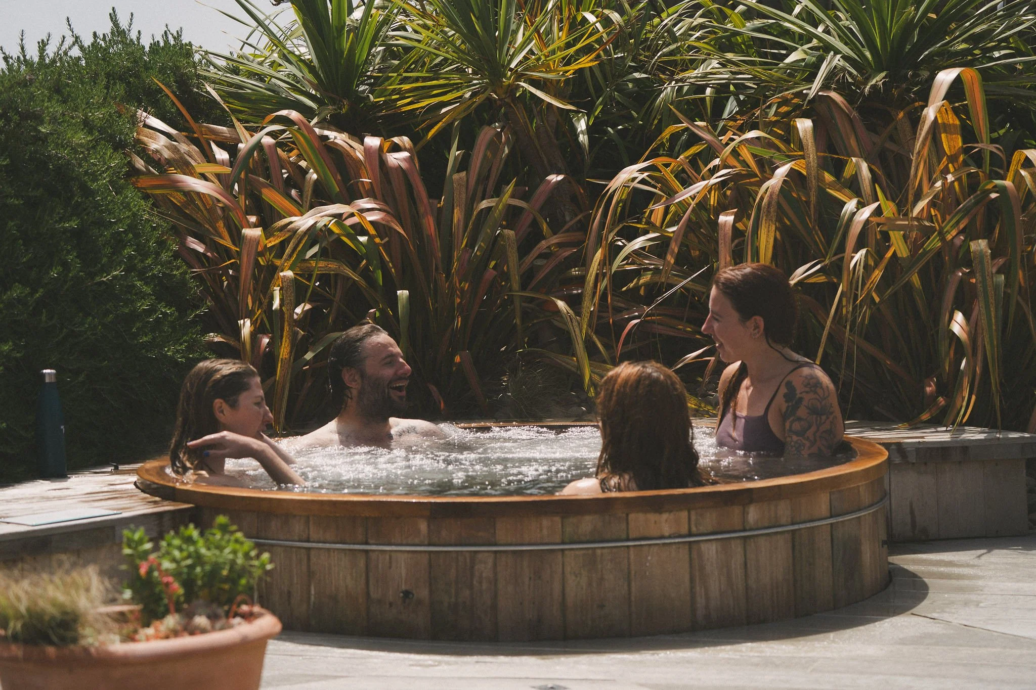 Guests relaxing together in a wooden hot tub at the Cornwall retreat house.