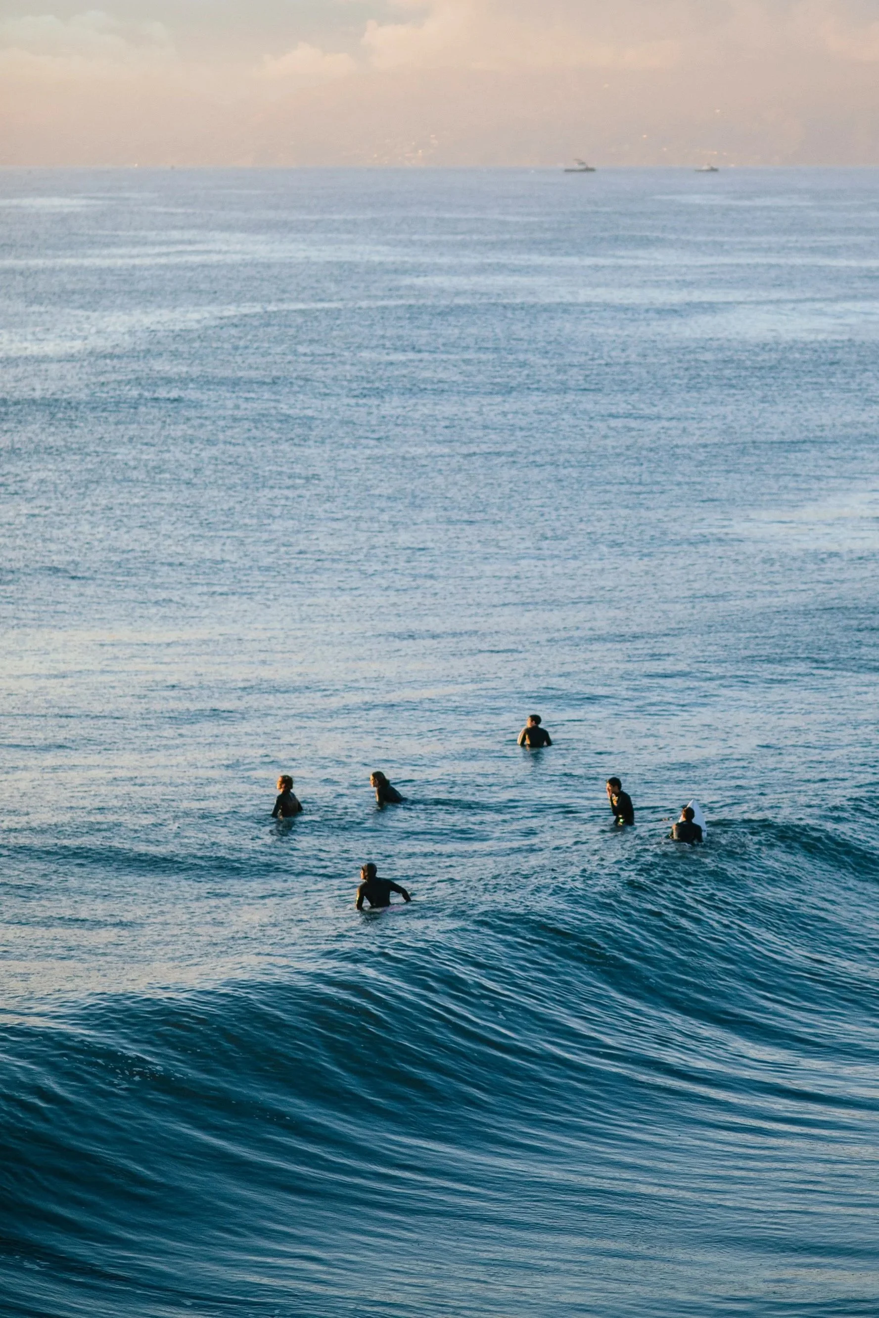 Surfers sitting together in the line-up off the coast at sunset