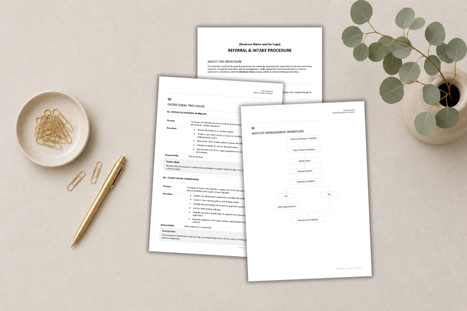 Three sheets of paper, a bowl of paper clips, a gold pen, and a potted plant on a light-colored table.