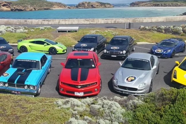 Green, red and silver supercars parked by the coastline