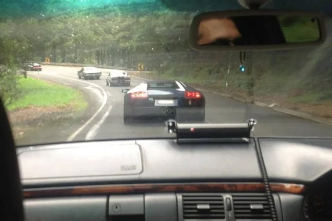 Rally cars driving a winding forest road on Cannonball Run Australia