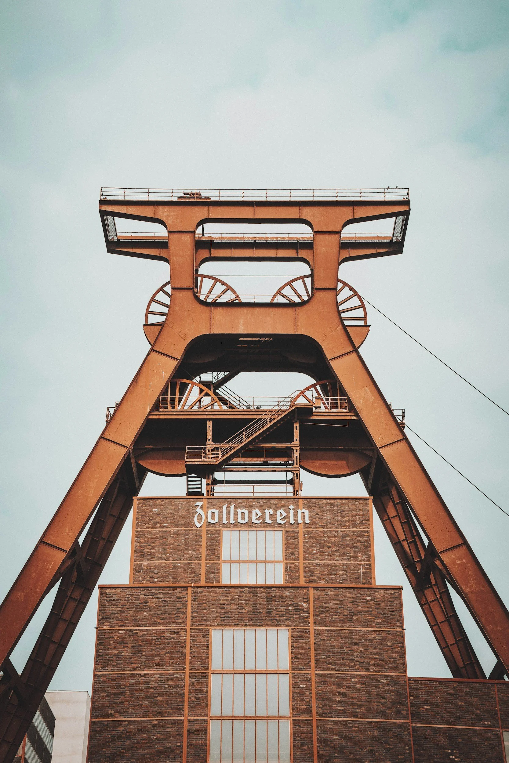 Ein Industrieturm aus rostigem Metall mit einer großen Holzfassade und Fenstern, auf der der Schriftzug "Zollverein" zu sehen ist, typisch für eine ehemalige Zeche in Deutschland.