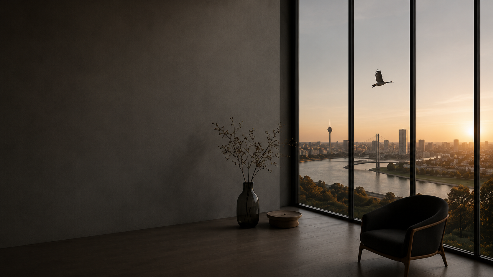 Innenraum mit dunklem Sofa, Vase mit Zweigen, kleiner runder Tisch vor großen Fenstern mit Blick auf eine Stadt bei Sonnenuntergang, Fluss und einen fliegenden Vogel.