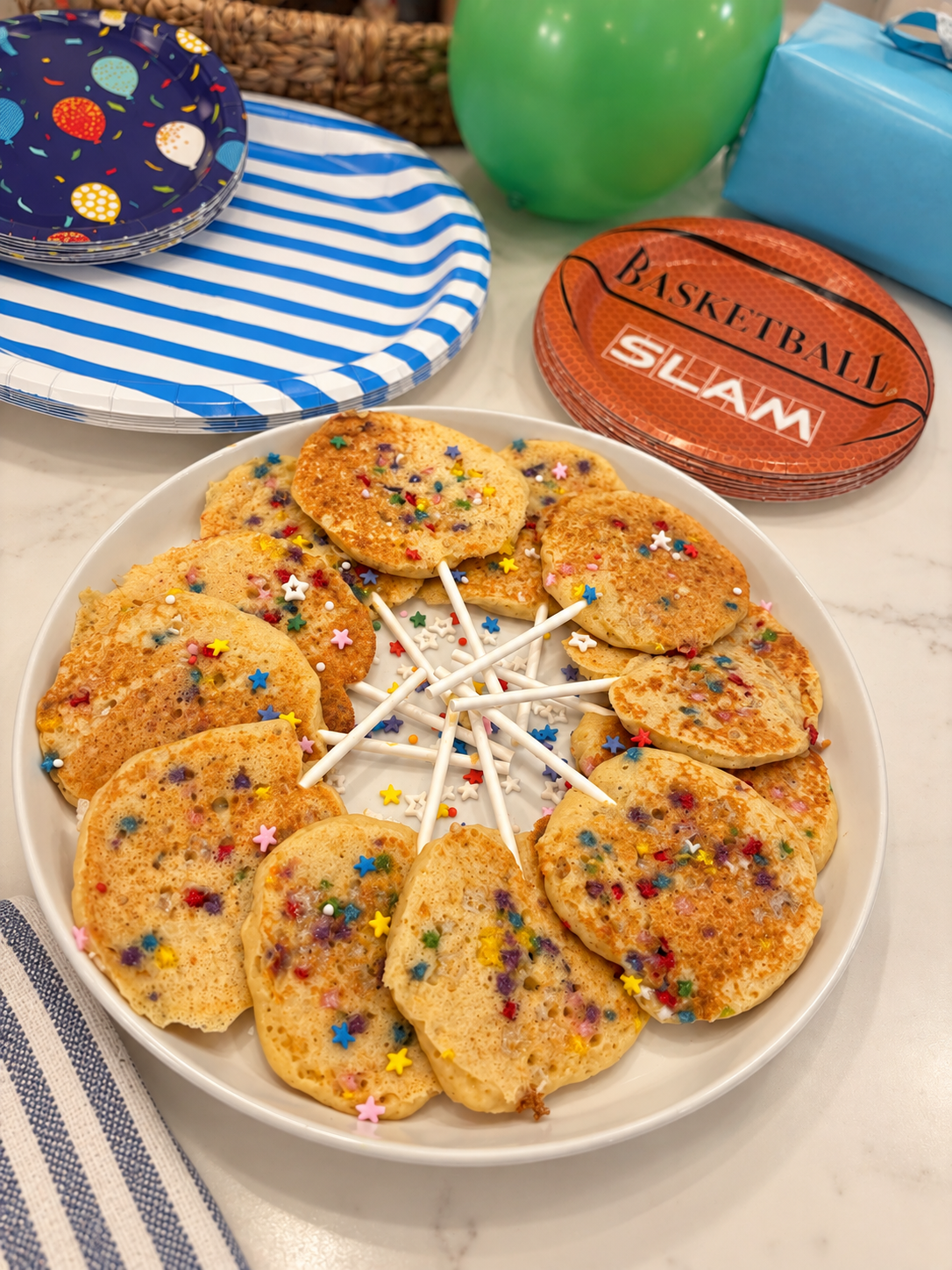 Homemade birthday pancake lollipops with colorful sprinkles arranged for a family birthday celebration.