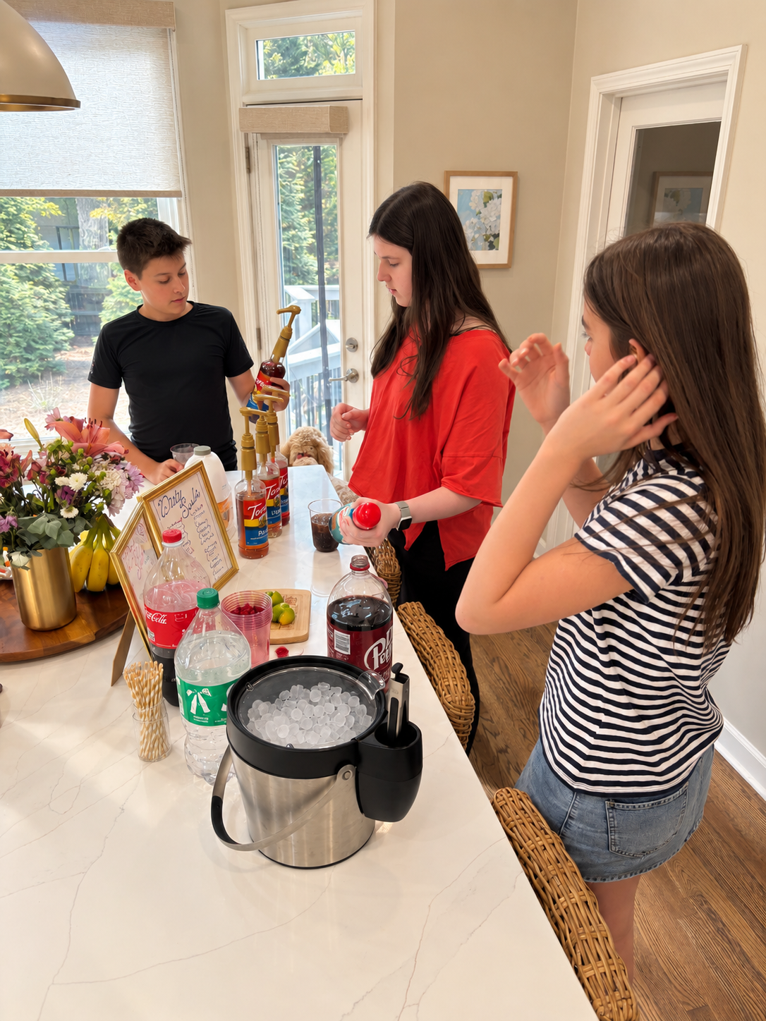 Teenagers making drinks together around the kitchen island at home.