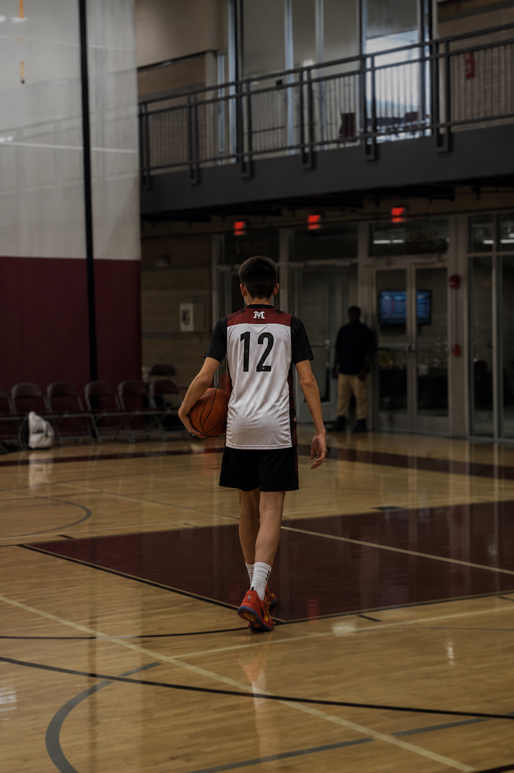 Son walking off court with basketball in hand.