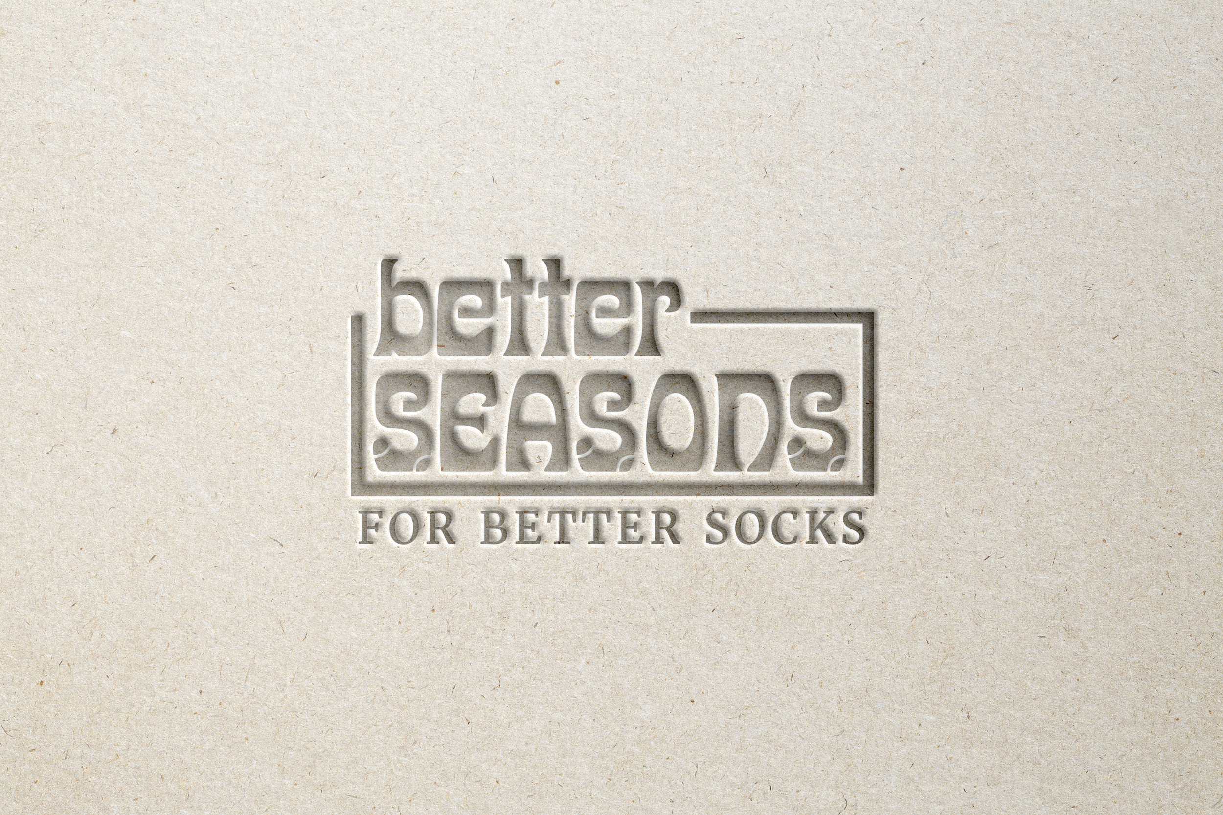 Text embossed on paper that reads 'Better Seasons for Better Socks' against a plain beige background.