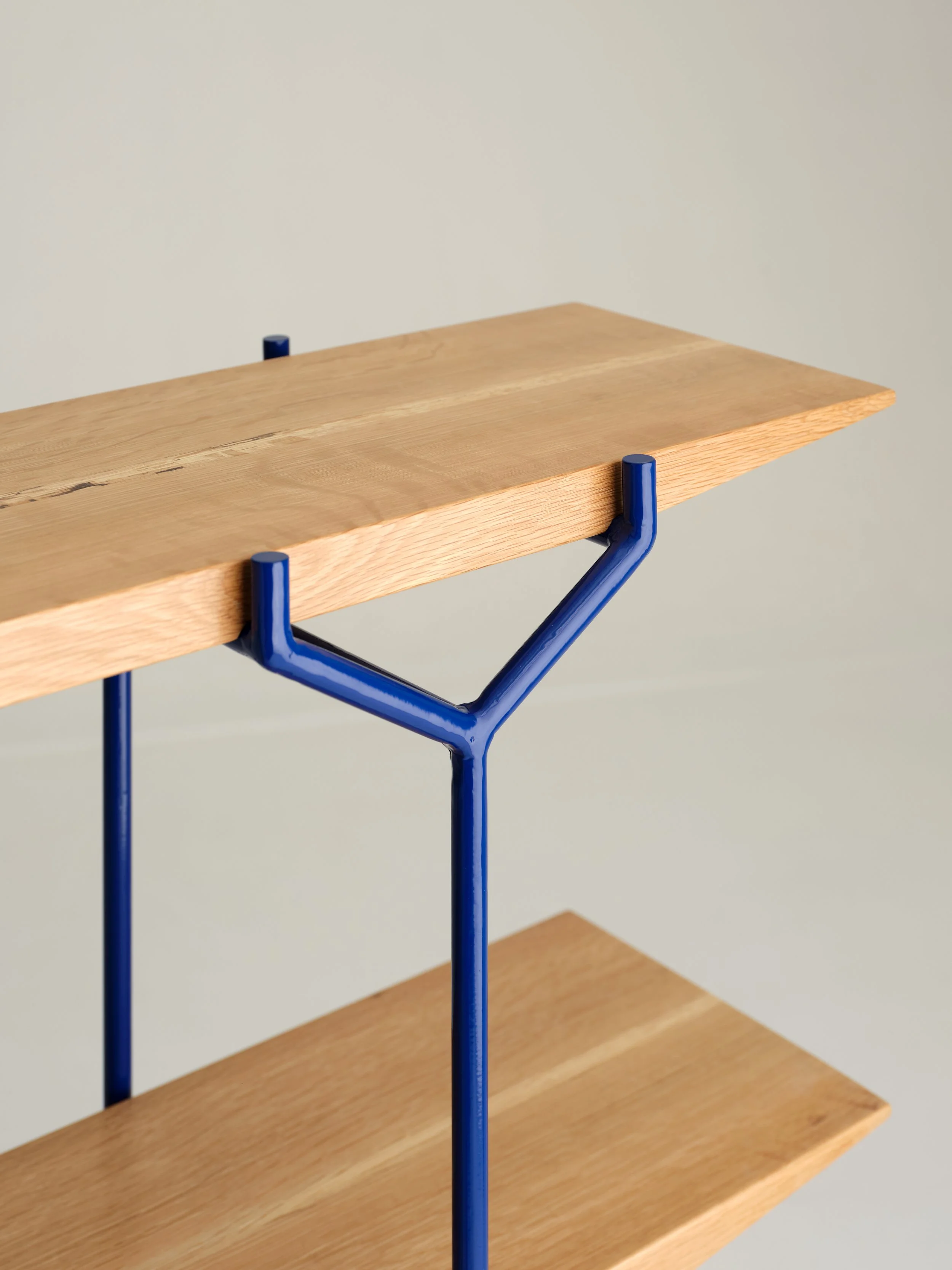 A wooden table with blue metal legs against a plain light-colored background.