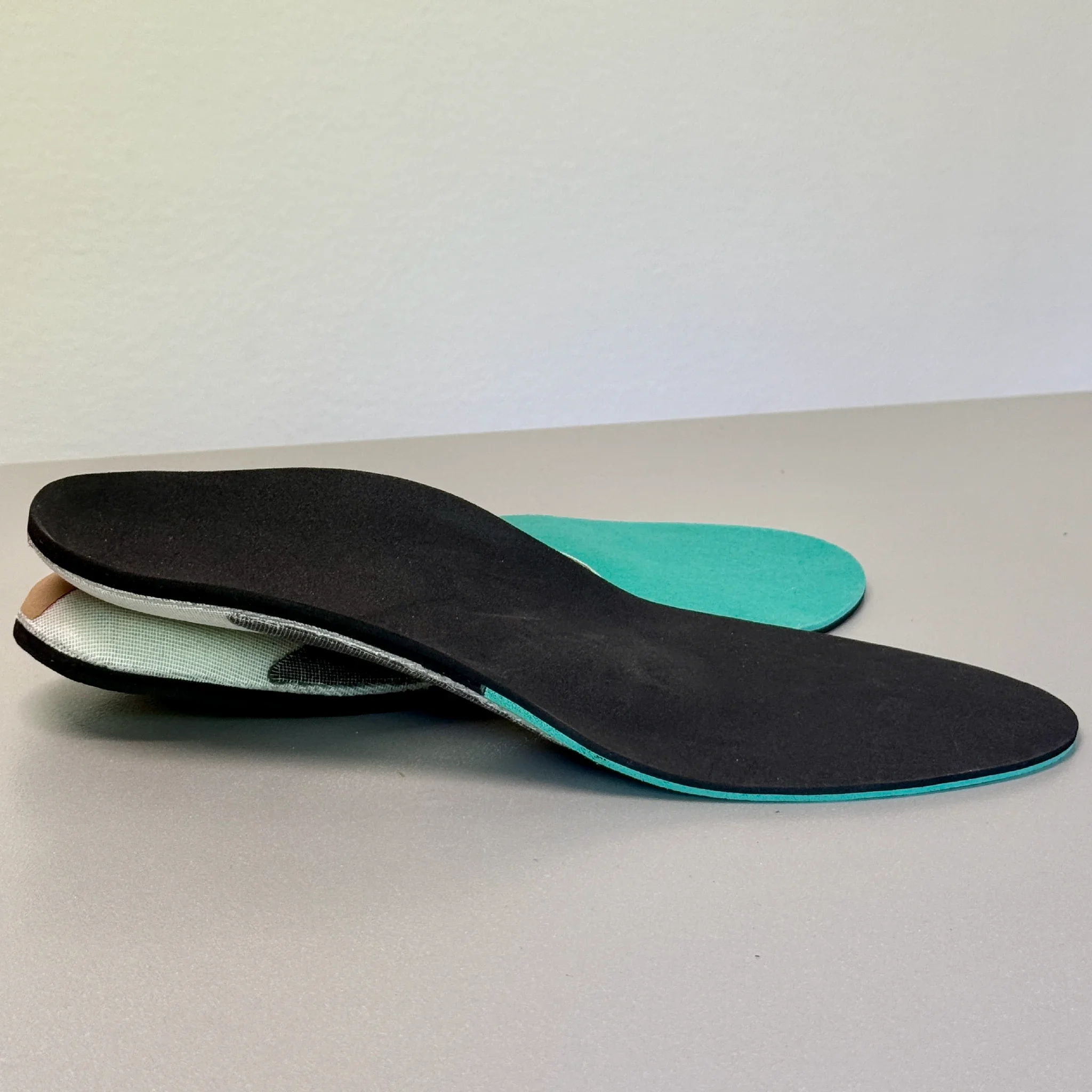 Une collection de semelles intérieures de différentes formes et couleurs empilées sur une surface grise.