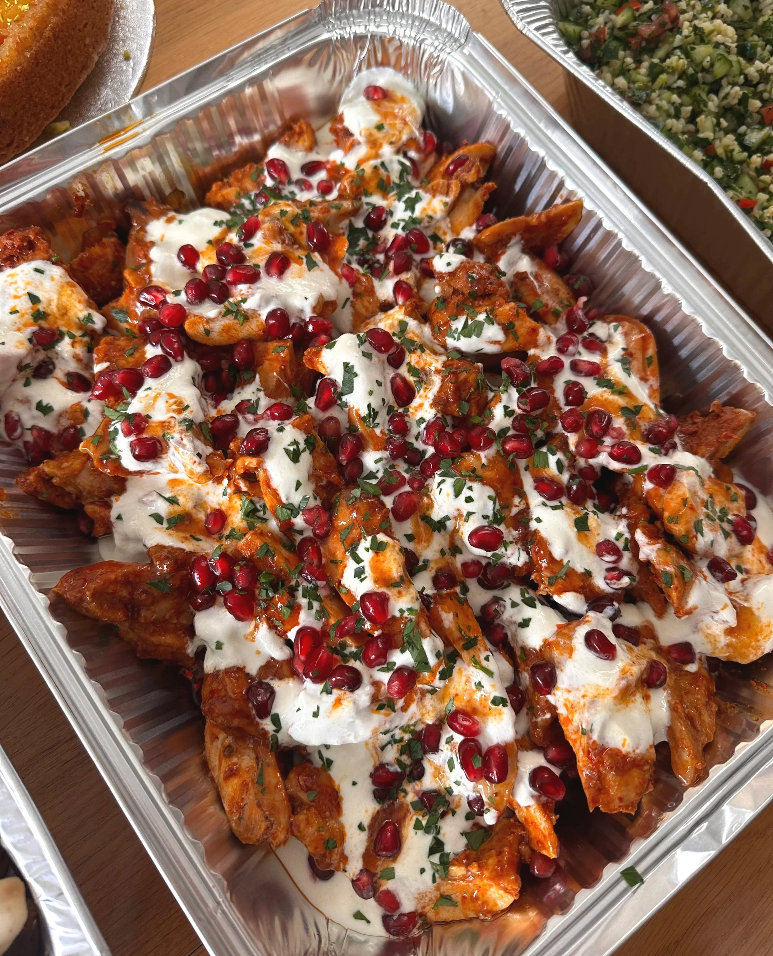 Hot-honey and harissa grilled chicken thighs topped with garlic yogurt, pomegranate seeds, and chopped parsley.