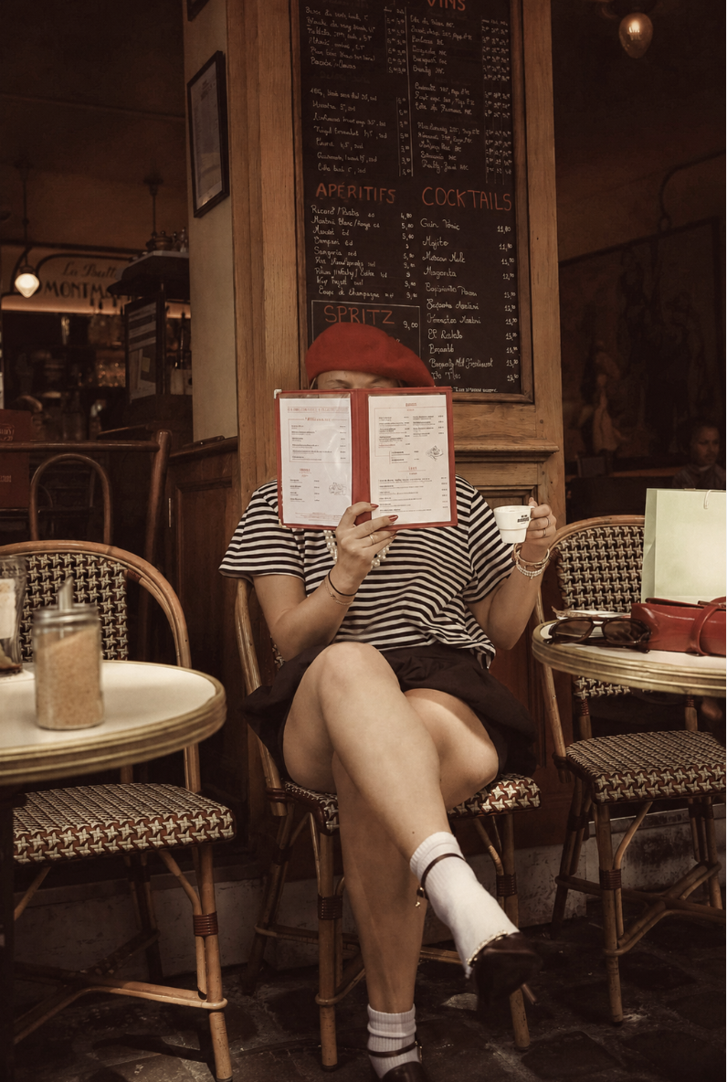 Vrouw met een rode baret leest een menukaart in een café.