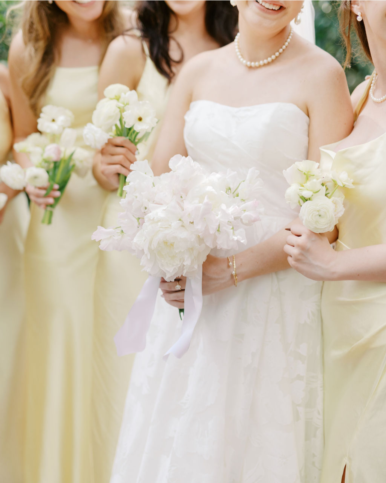 Bridesmaids and bride holding bouquet of white flowers at wedding.