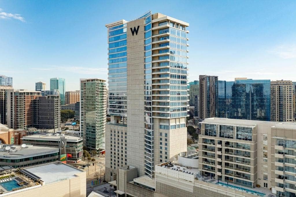City skyline with tall modern buildings, including a high-rise with a large 'W' logo, under a clear blue sky.