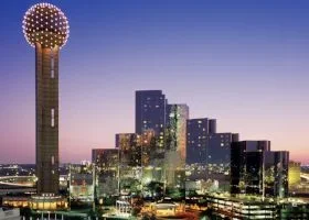 Nighttime cityscape of Dallas, Texas, with the Reunion Tower featured prominently and illuminated skyscrapers.