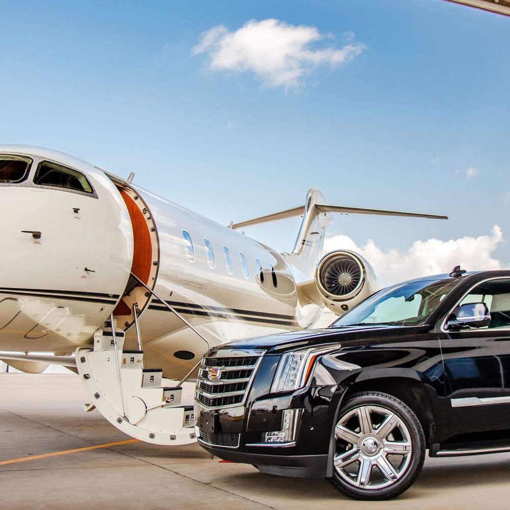 A private jet parked at an airport with a black Cadillac SUV in front of it.