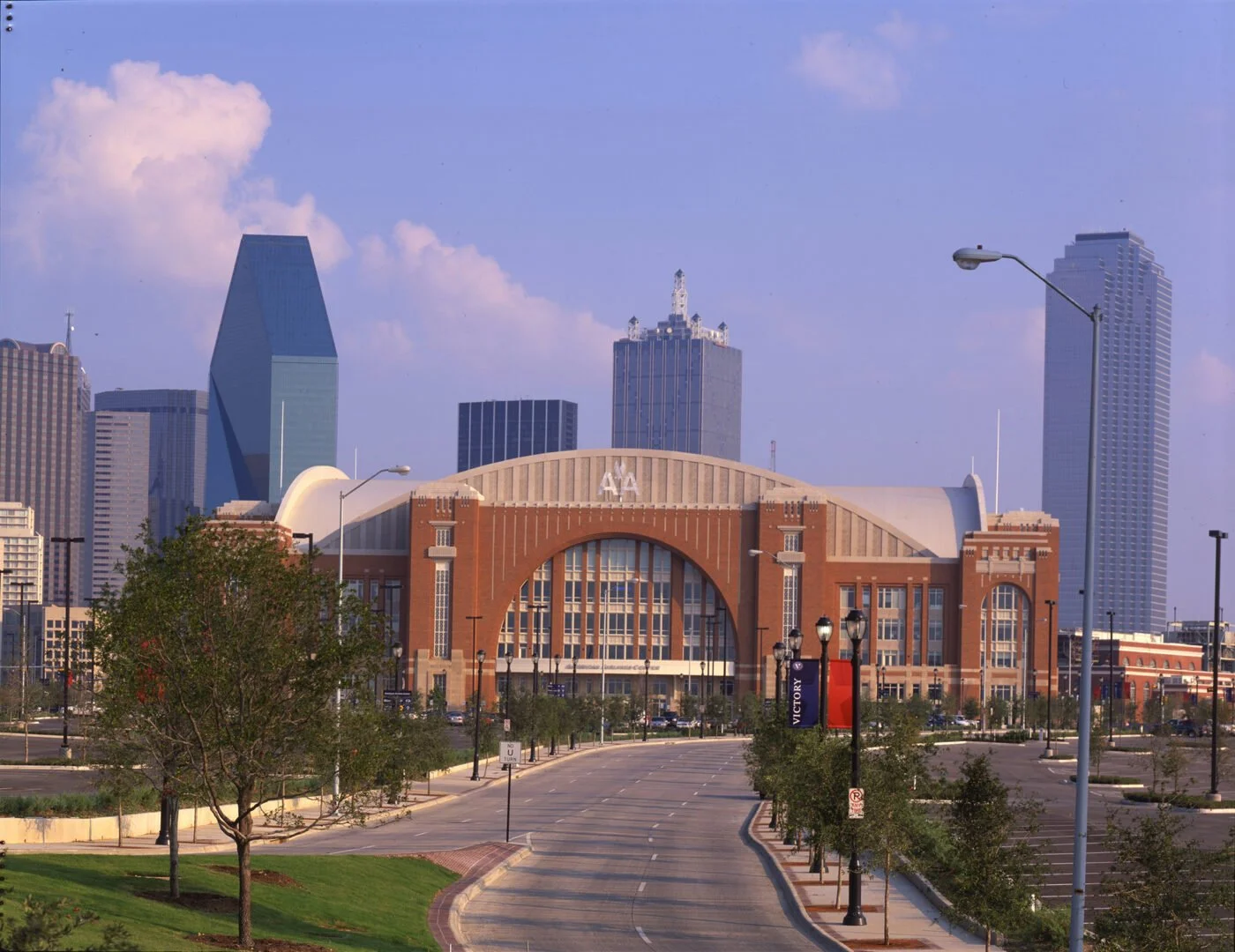 Skyline of downtown Dallas, Texas, including the historic Union Station building in the foreground, with modern skyscrapers in the background and clear blue sky.