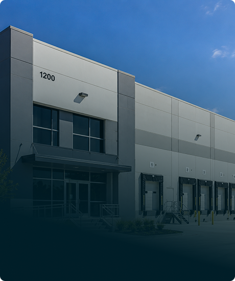 Exterior of a modern warehouse or distribution center with loading docks and a partly cloudy sky.