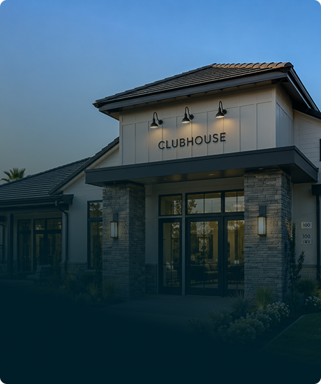 Exterior of a clubhouse building with a sign that says 'Clubhouse' above the entrance, during twilight.