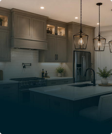 Modern kitchen with gray cabinets, stainless steel appliances, pendant lighting, and a white countertop island with a black faucet.