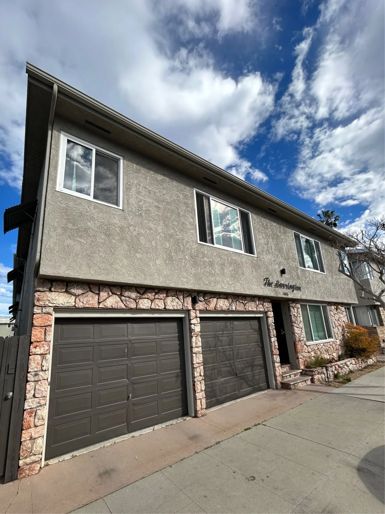 Multifamily building painted in a modern color scheme with natural stone. Beige and Gray accents with Urban Bronze garage doors.