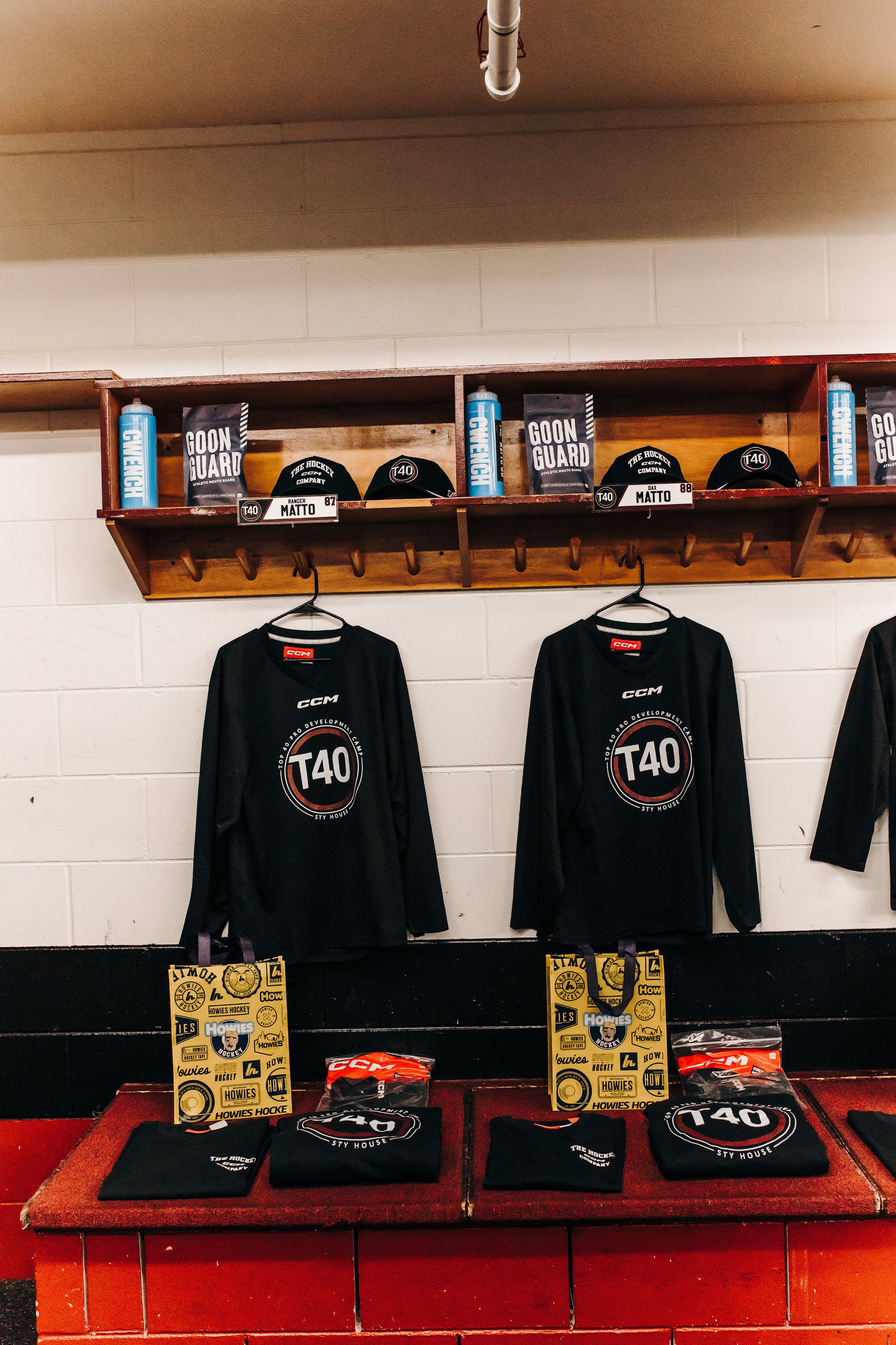 Hockey goalie equipment and apparel on display, including black hockey jerseys, hats, water bottles, and promotional signs for hockey gear and accessories.