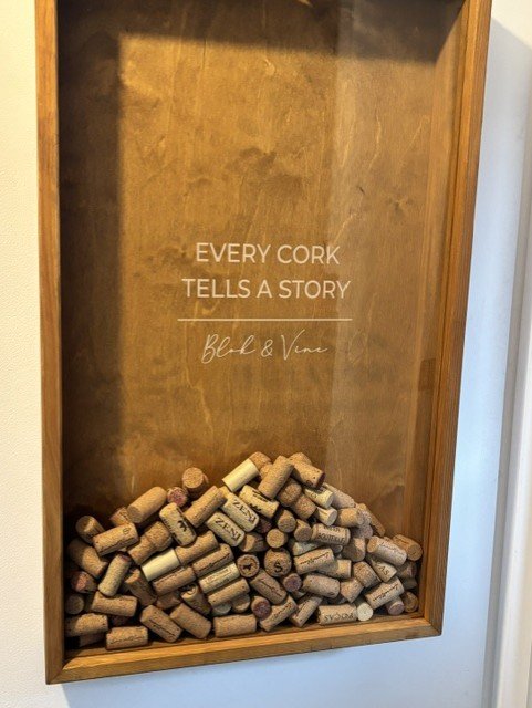 A display case filled with wine corks and a sign that reads "Every cork tells a story. Blod & Vino."