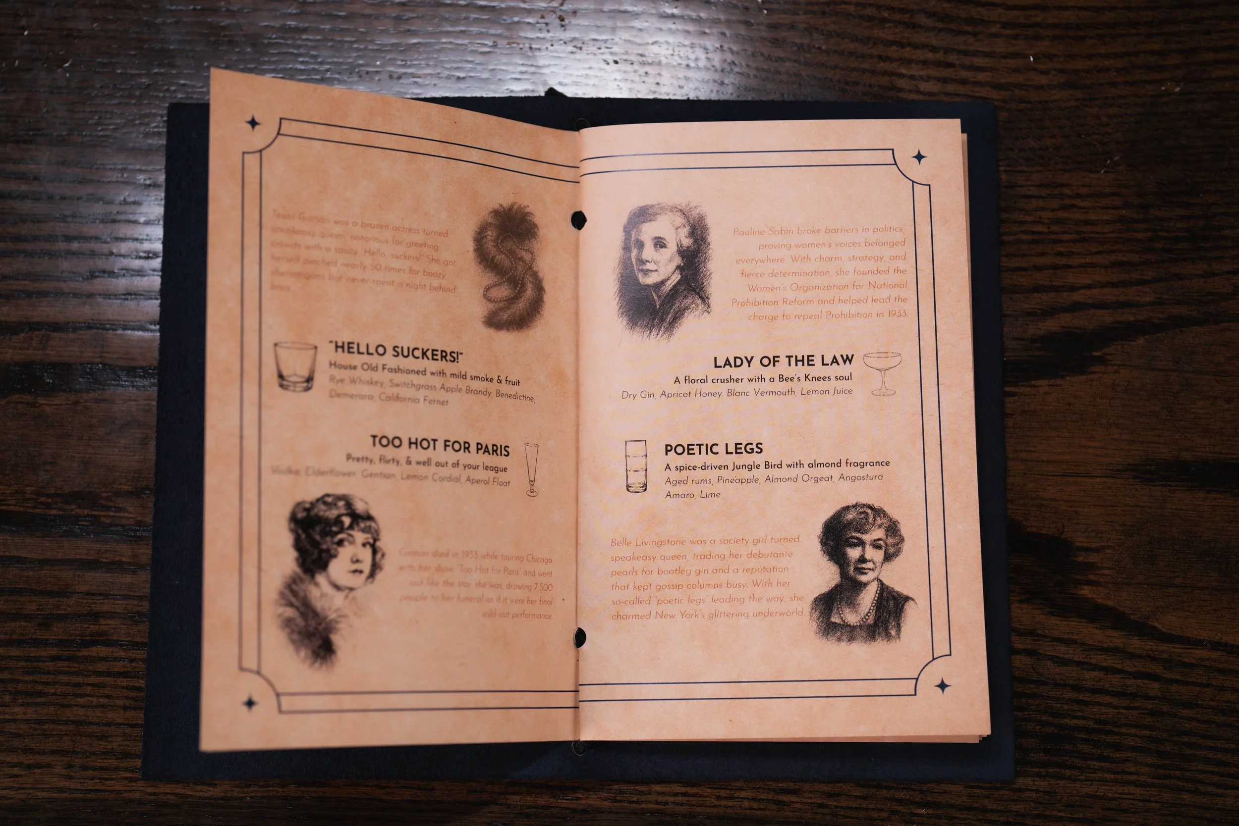 Open vintage-style menu with sketches and biographical text on a dark wooden surface.