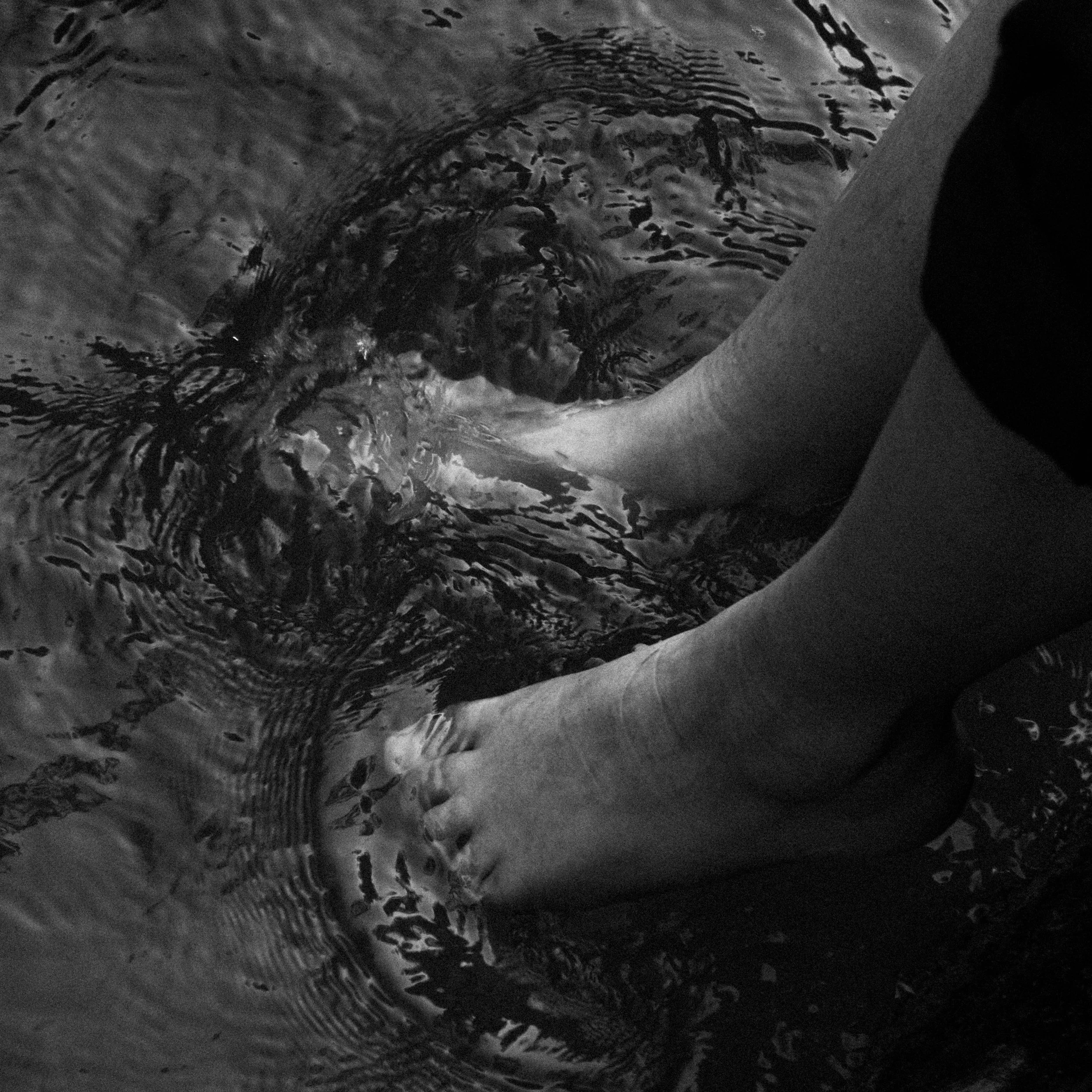 Close-up of a circular water ripple pattern on a dark surface, possibly water with reflections or movement.