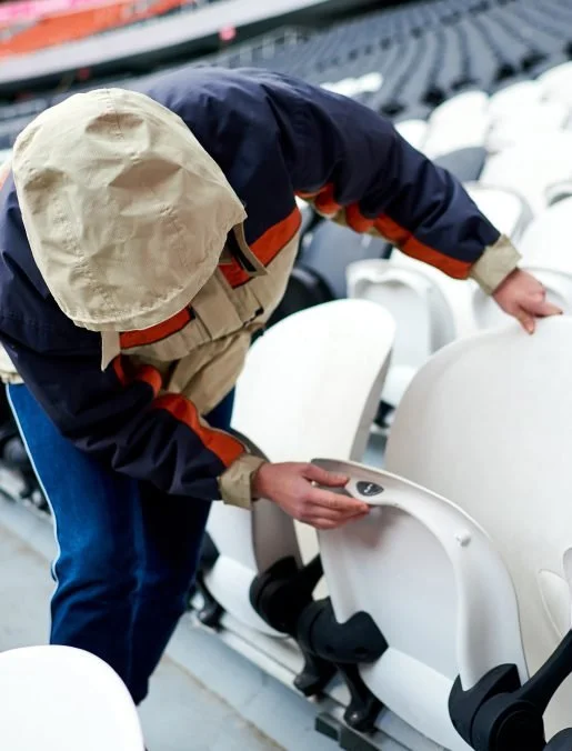 Person adjusting seats in a stadium or arena.