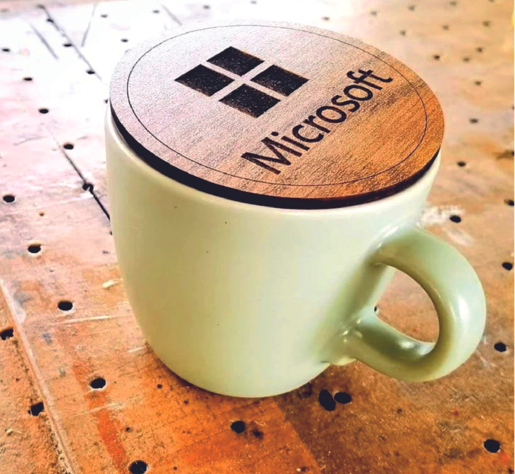 A white Starbucks coffee mug with a wooden lid featuring the Starbucks logo, placed on a wooden table with holes.