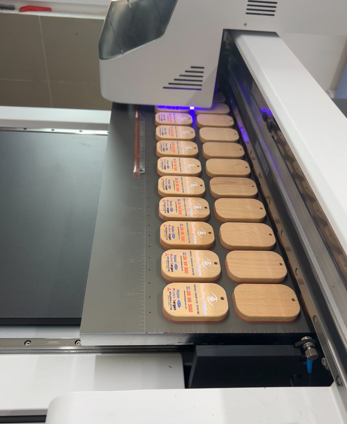 Embroidery machine creating wooden tags with printed labels.