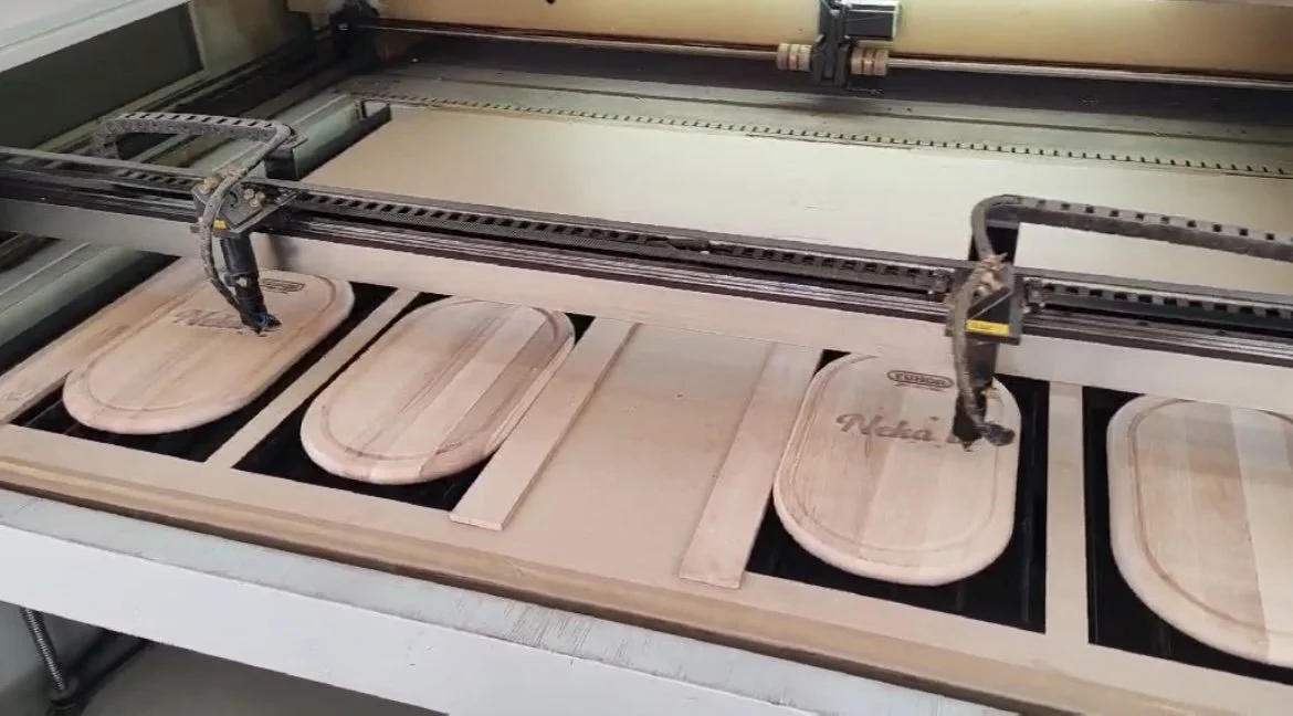 Wooden cutting boards with engraved designs being cut by a CNC machine.