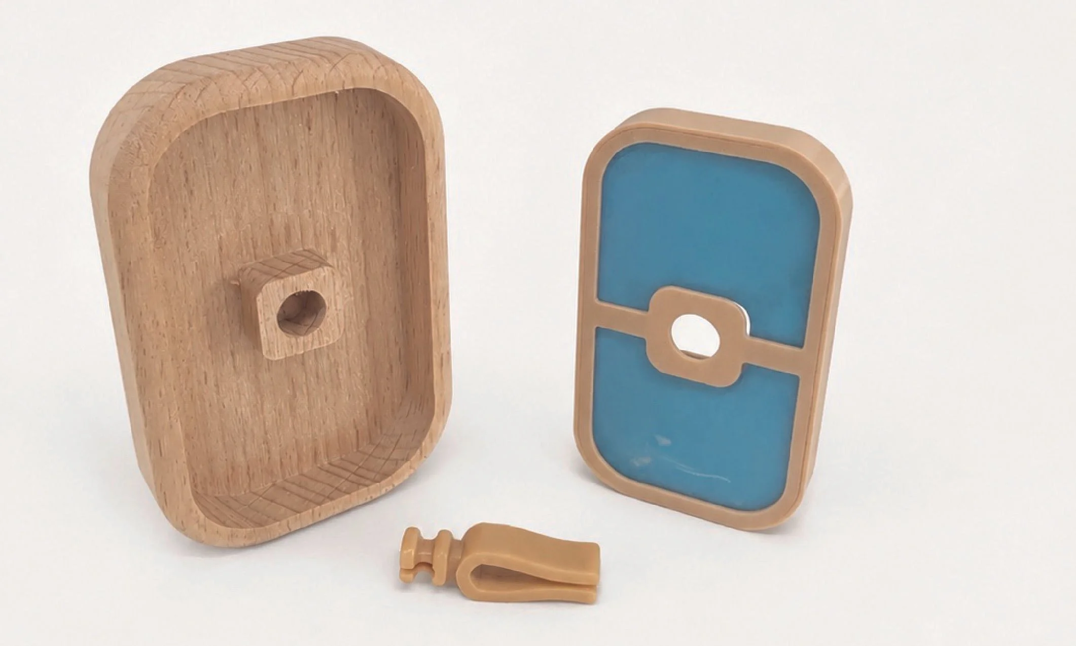 Two wooden toy objects resembling stylized skulls with key-like attachments, one with blue interior and one with natural wood finish, on a white background.