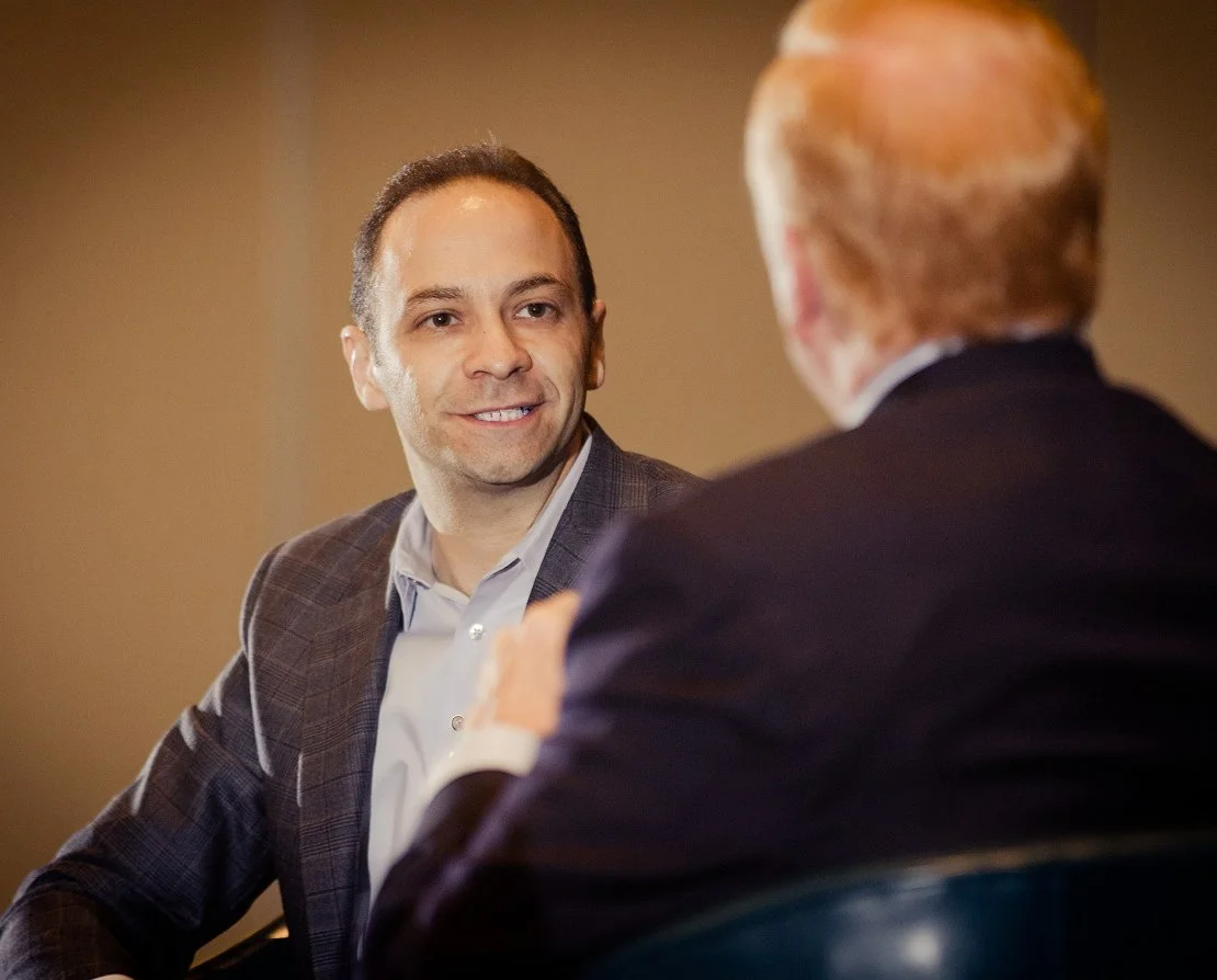 ron friedman sitting across from a person in the middle of an interview