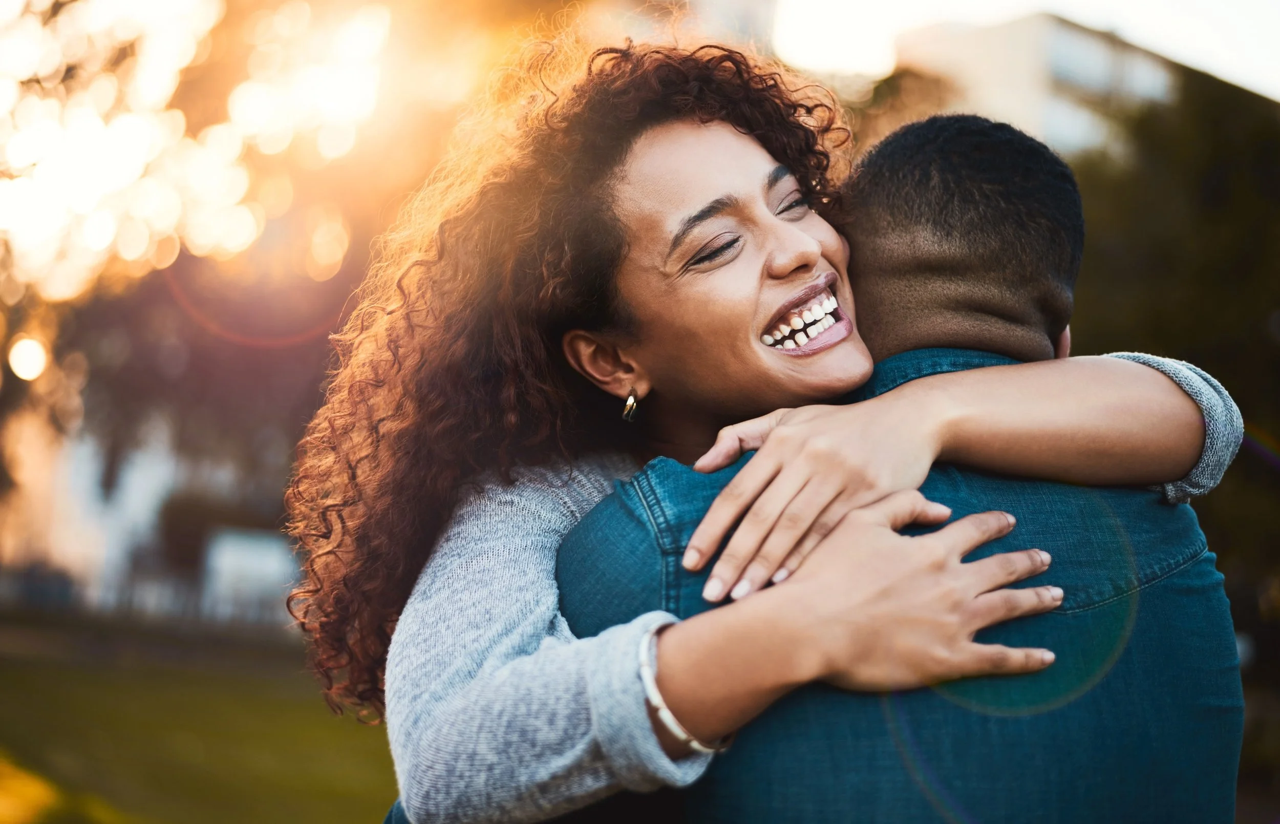 Joyful black couple hugging in a park at sunset