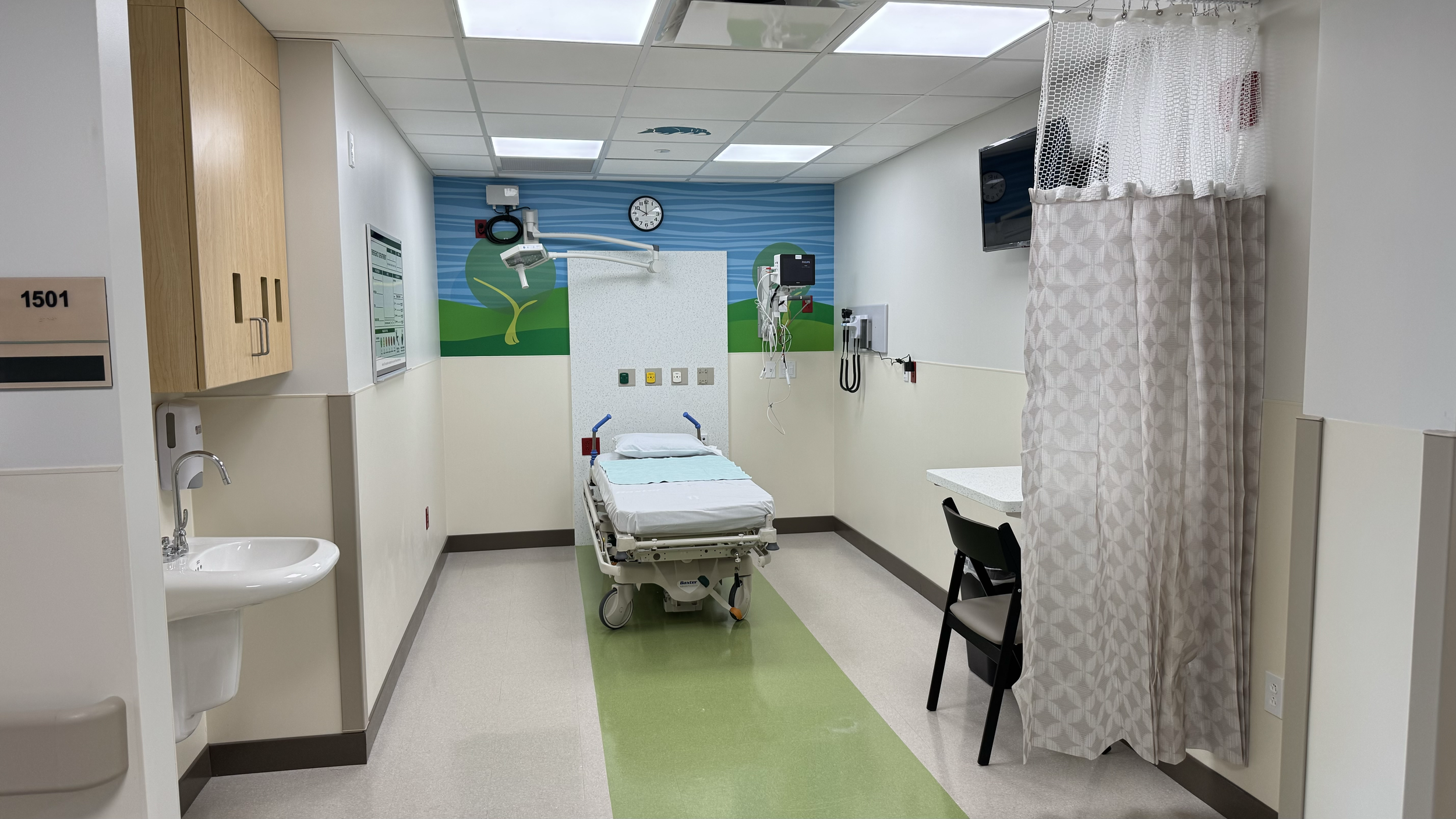 Rivers Health pediatric emergency treatment room with patient bed, medical equipment, privacy curtain, and child-friendly finishes.