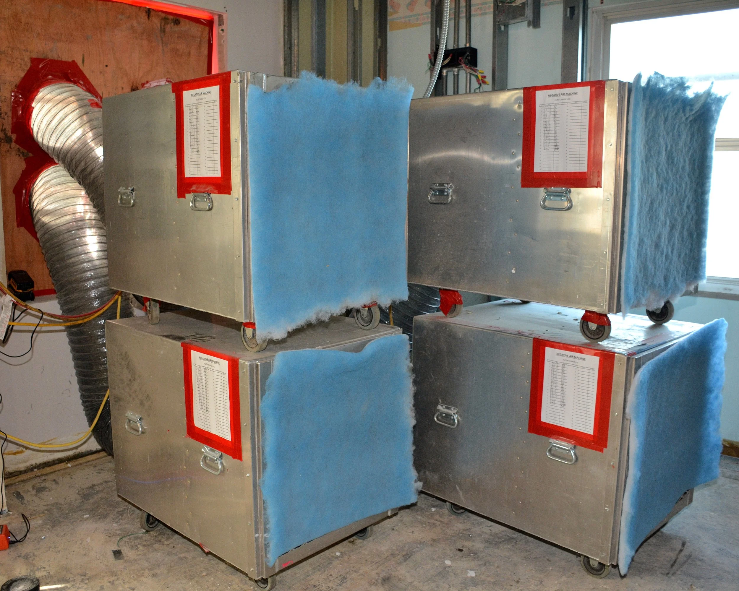 Negative air machines staged for use in controlling dust and airborne contaminants during occupied-facility construction.