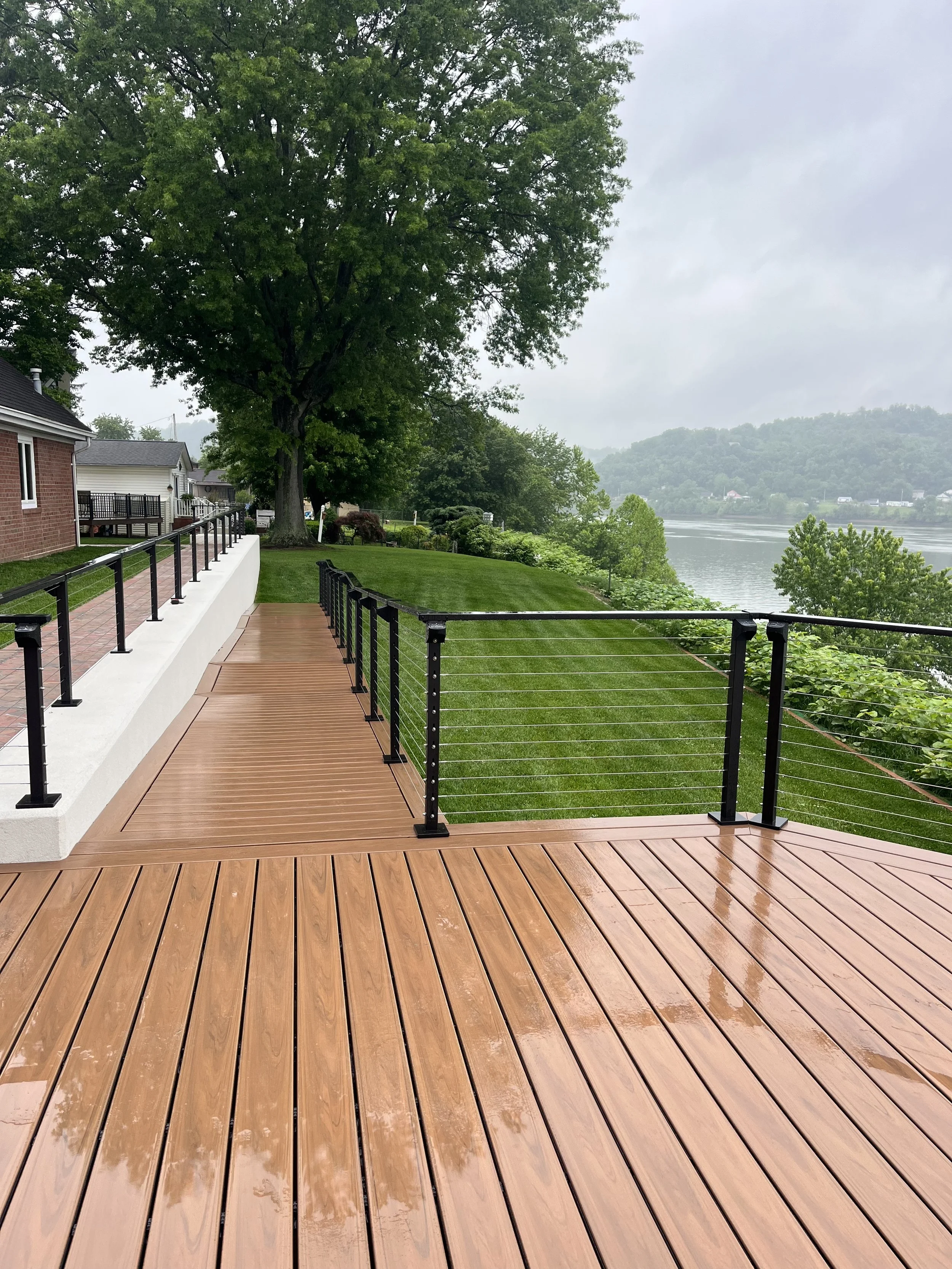 Completed riverfront deck, cable railing, retaining wall and restored lawn overlooking the Ohio River.