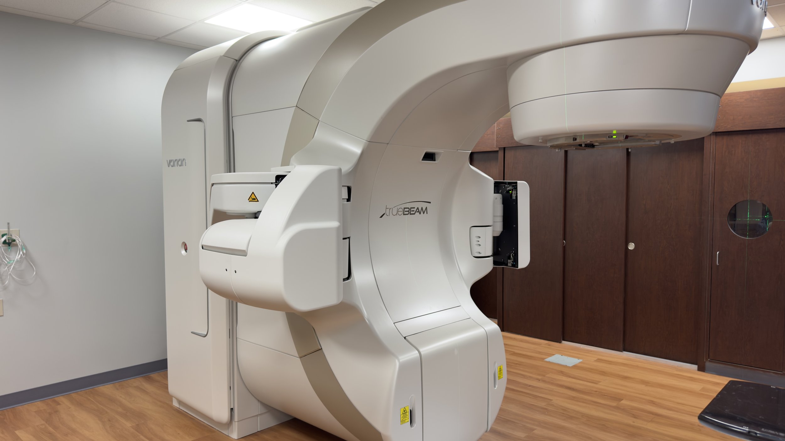 Varian TrueBeam linear accelerator beside wood-paneled radiation shielding doors in the renovated St. Mary’s treatment suite.