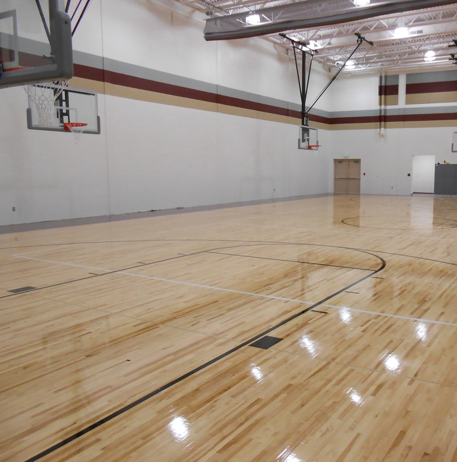 Mingo County school gymnasium featuring a finished wood basketball court, basketball goals and exposed structural ceiling.
